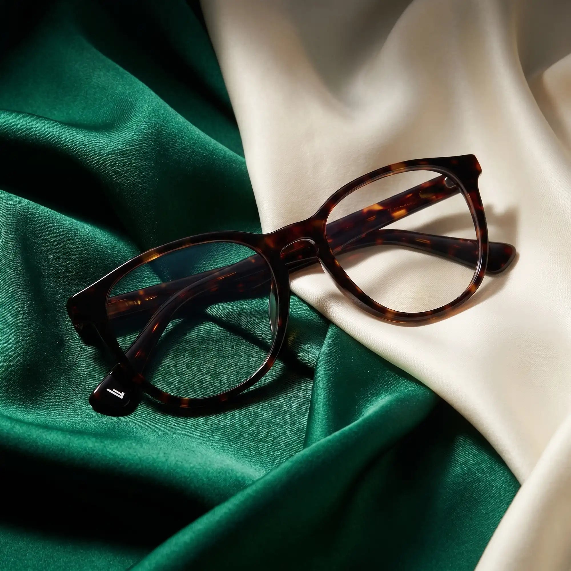 Fiore 7046 eyeglasses in tortoiseshell – resting on draped emerald and ivory silk