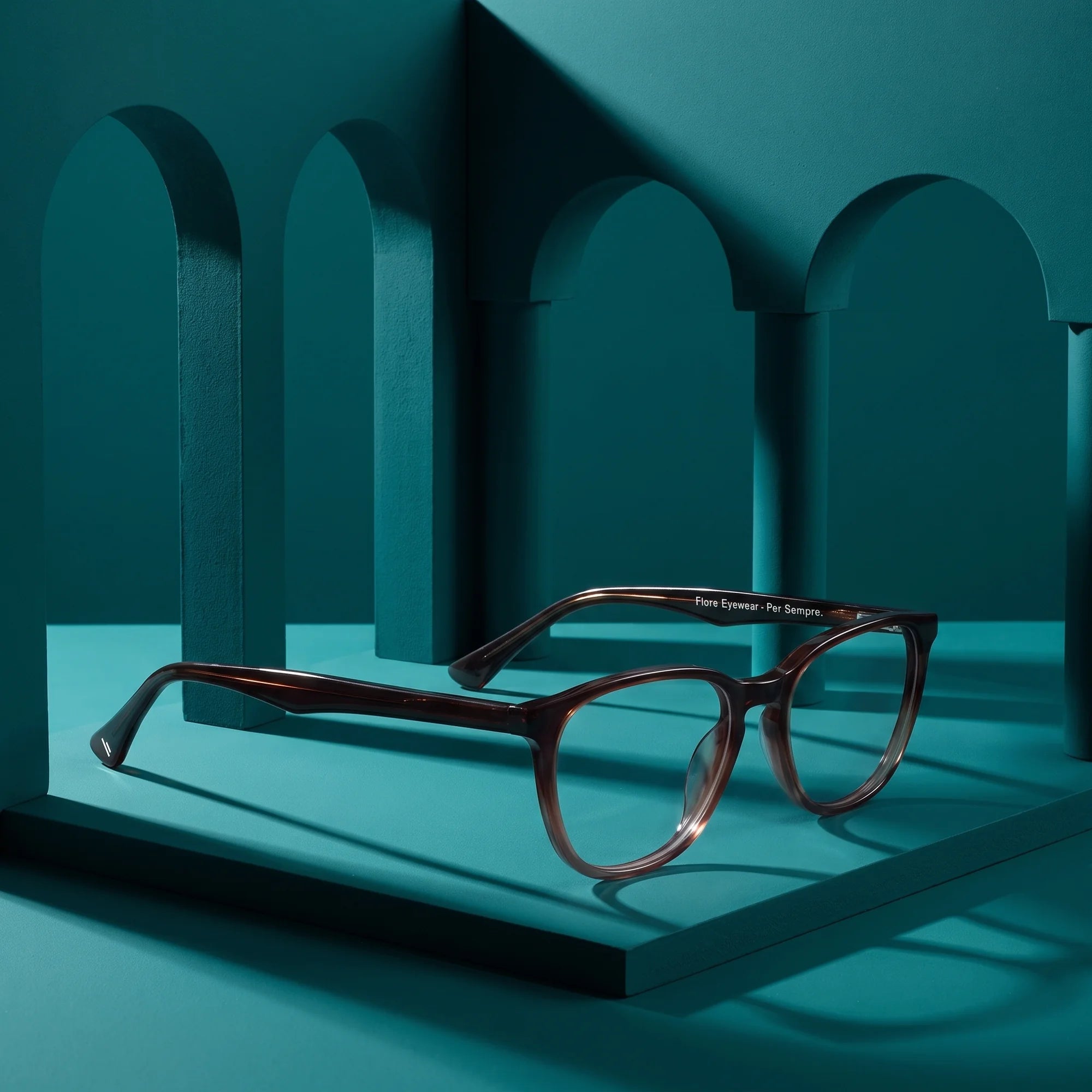 Fiore 7046 eyeglasses in gradual brown – still life among monochrome teal arches