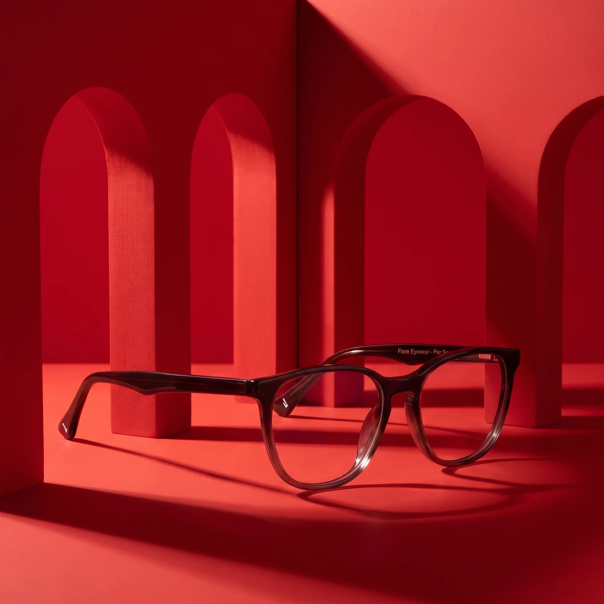 Fiore 7046 eyeglasses in gradual brown – staged on a sculptural vivid red architecture set