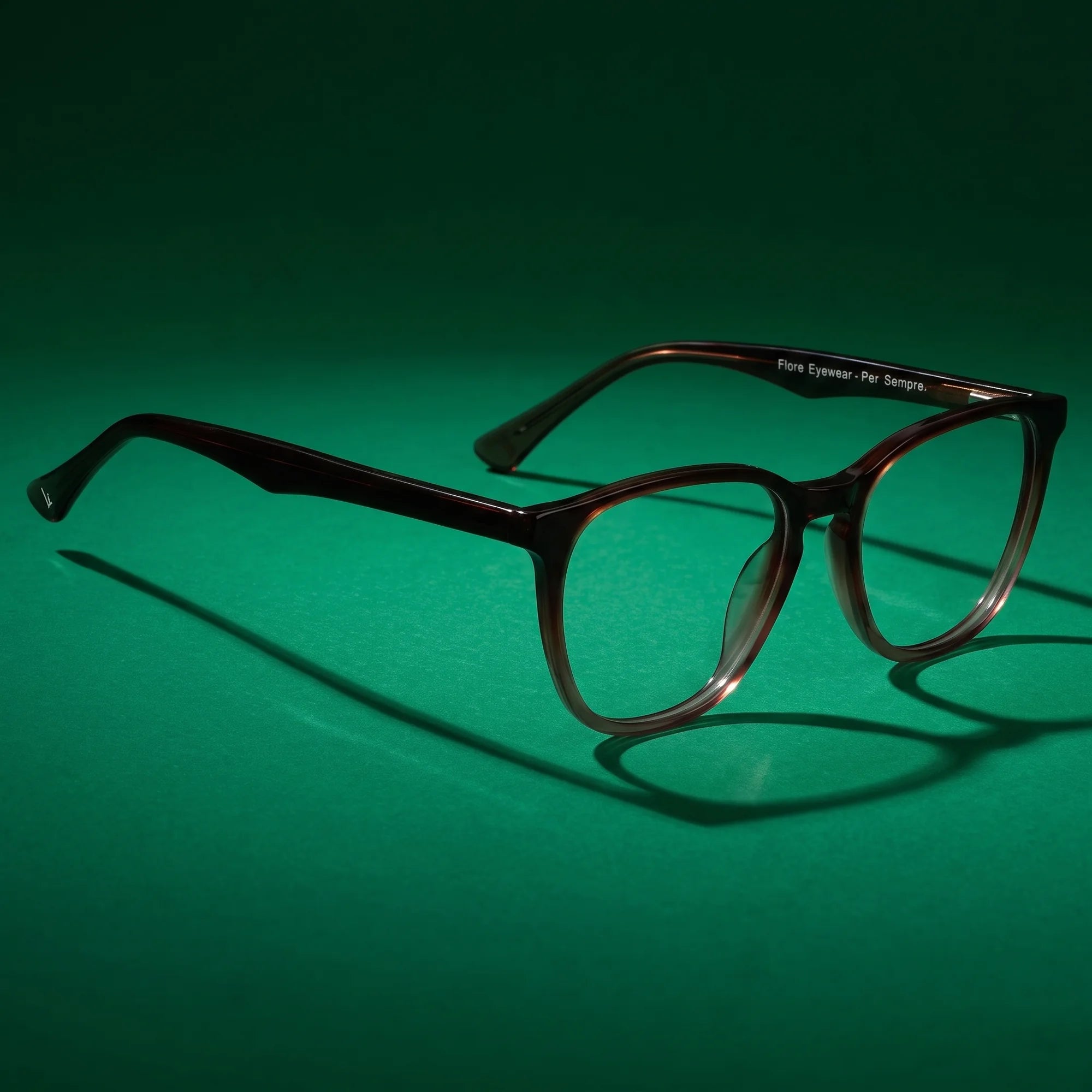 Fiore 7046 eyeglasses in gradual brown – editorial still life on a saturated emerald set