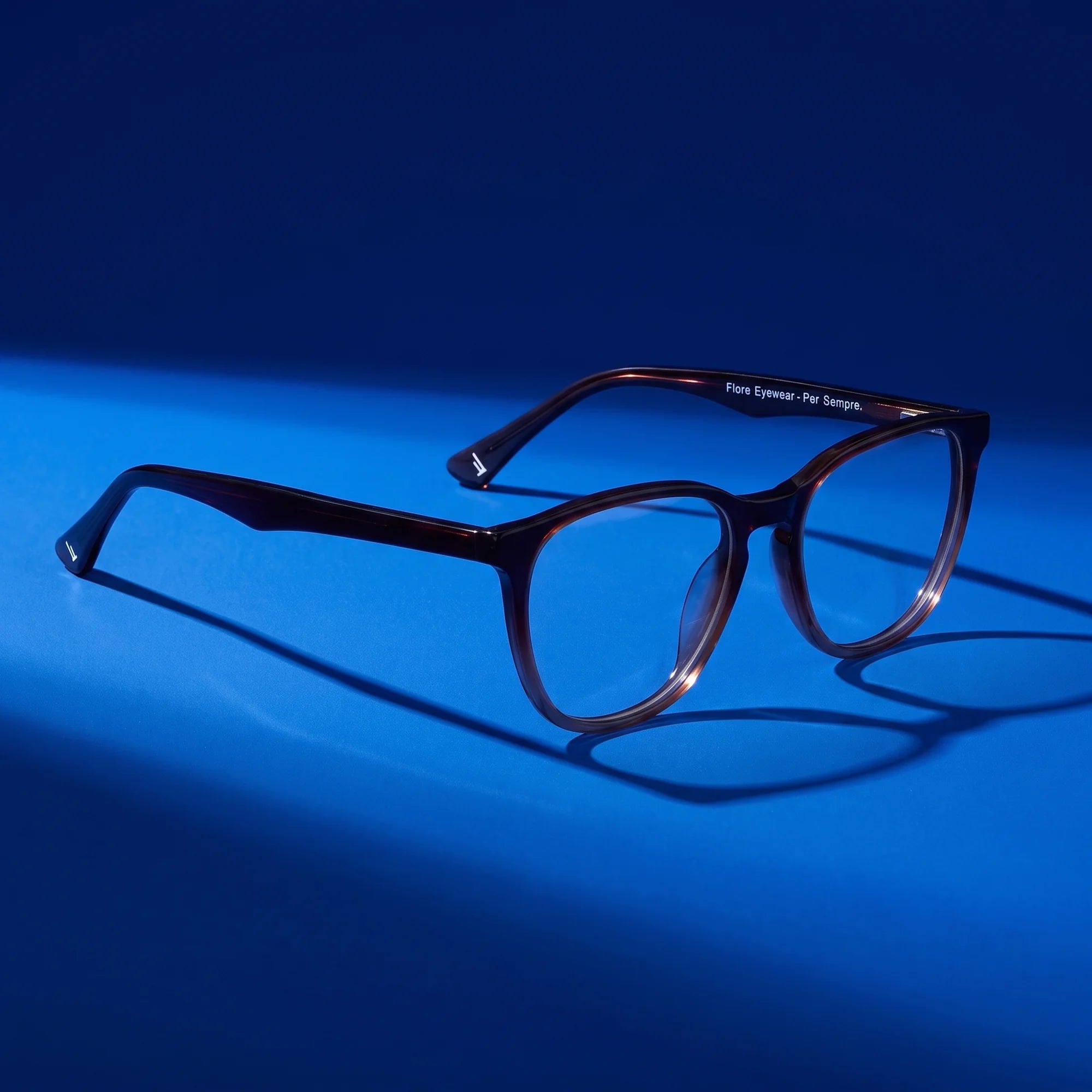 Fiore 7046 eyeglasses in gradual brown – still life on a seamless cobalt studio backdrop