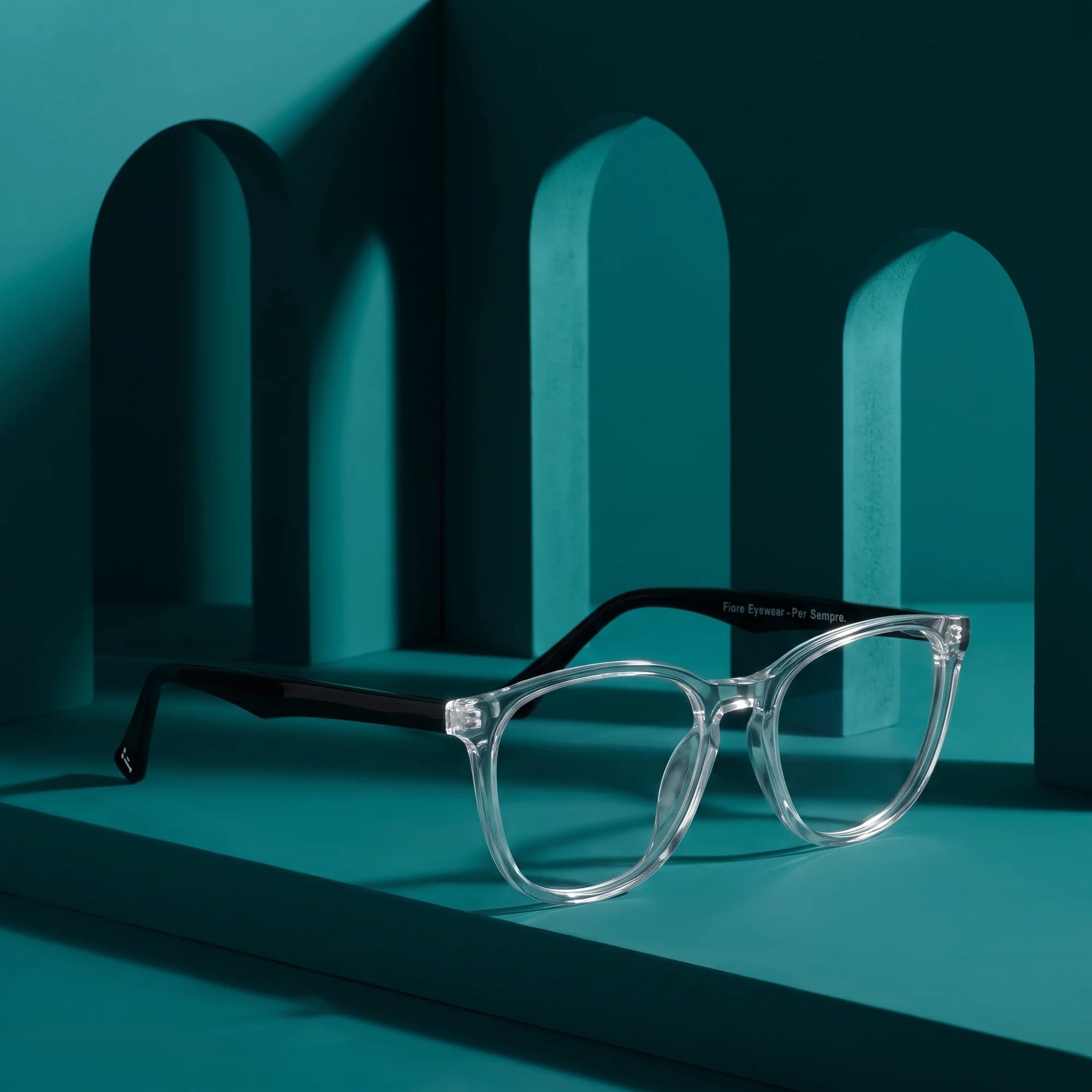 Fiore 7046 eyeglasses in transparent – staged on a sculptural teal architecture set