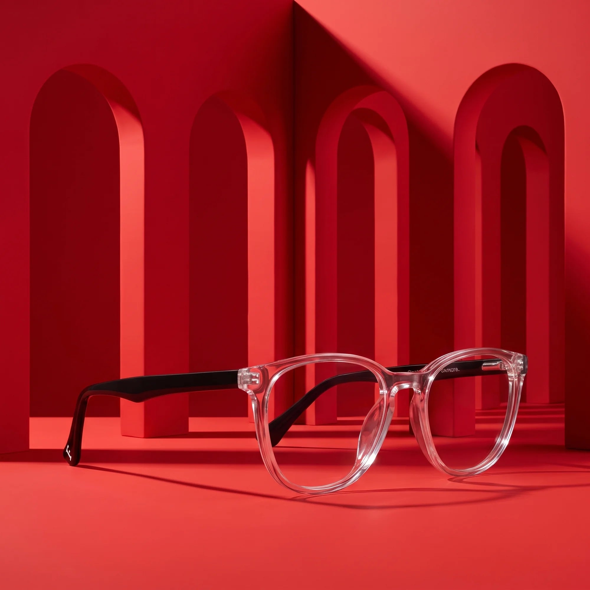 Fiore 7046 eyeglasses in transparent – displayed on a vivid red podium among arches