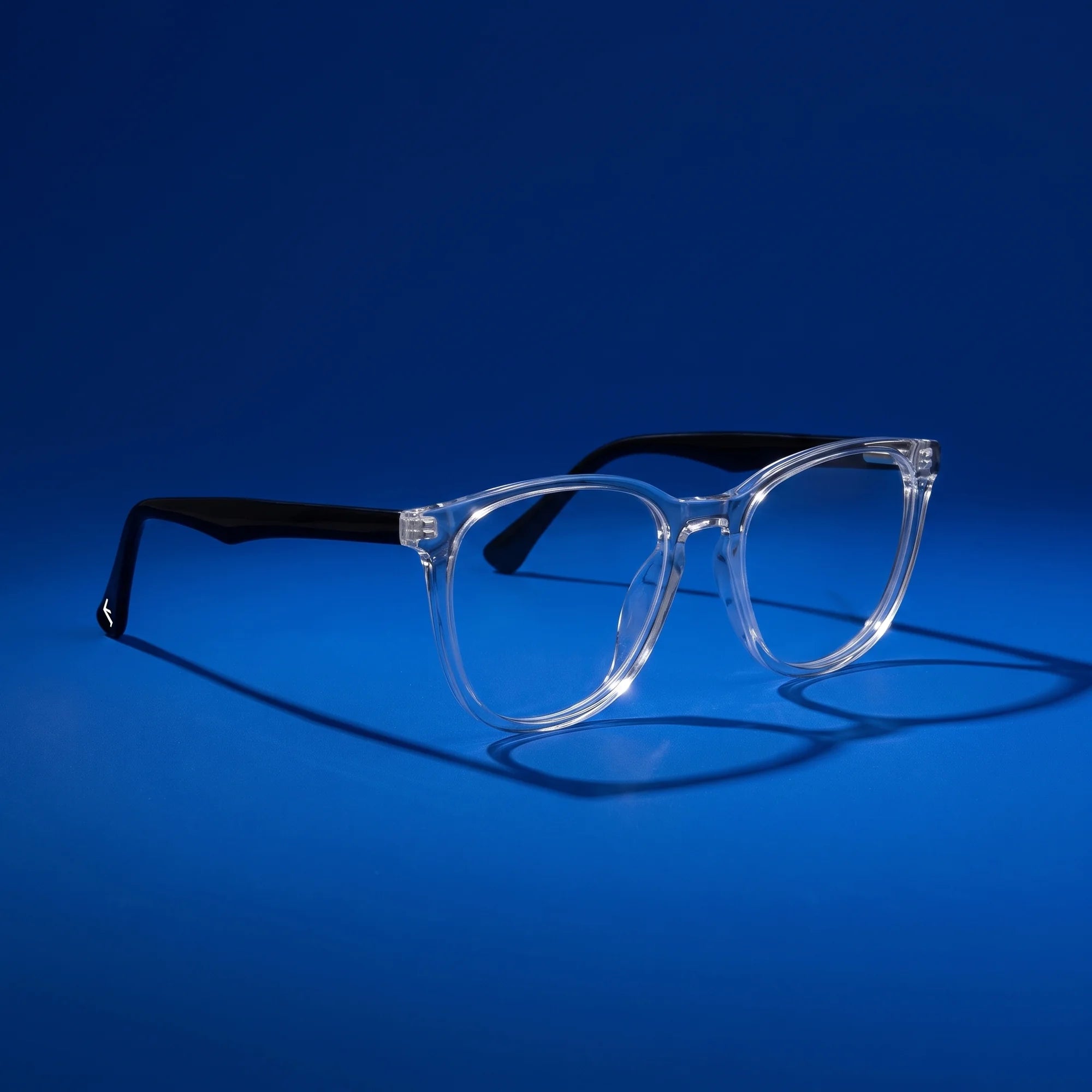 Fiore 7046 eyeglasses in transparent – hero still life against a deep cobalt backdrop
